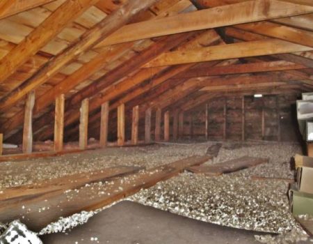 An attic built with black spruce wood was photographed in Ontario, Canada. Vermiculite insulation and stored boxes show in the image.